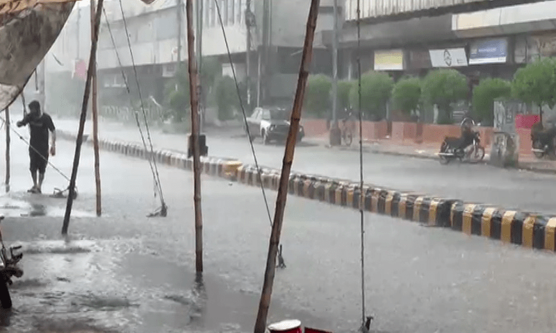 A man walks on a footpath near a waterlogged road on Saturday. —DawnNewsTV