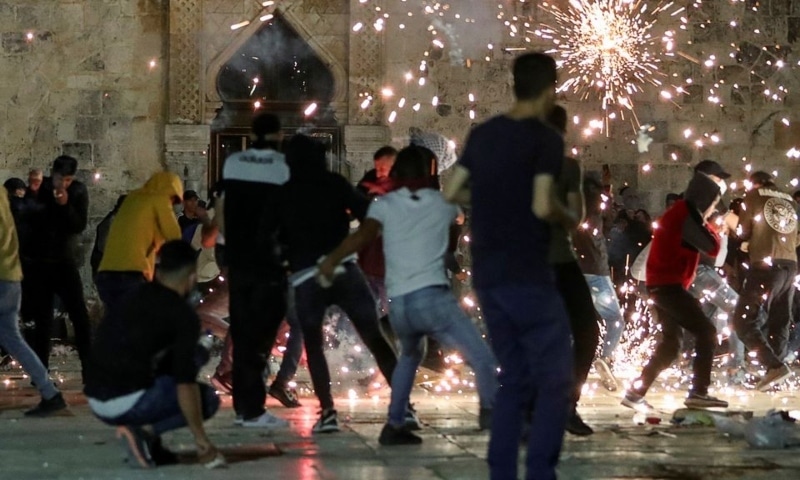 Palestinians react as Israeli police fire stun grenades during clashes at the compound that houses Al Aqsa Mosque on Friday.  — Reuters