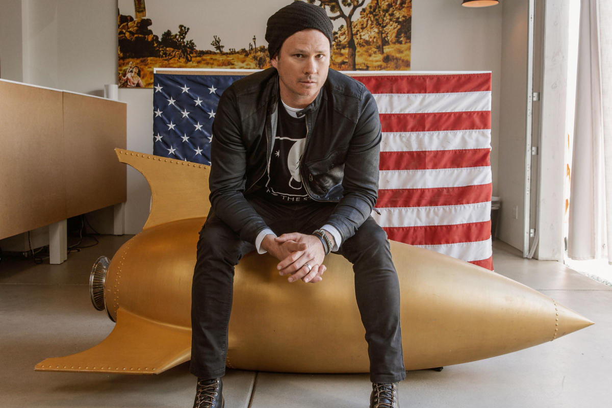 Tom Delonge sits on a rocket shaped chair.