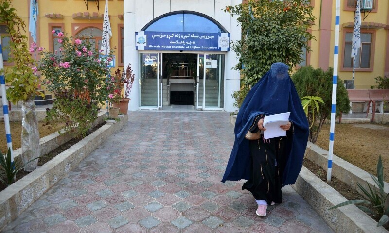 <p>A female university Student walks in front of a university in Kandahar, Afghanistan on Dec 21. — AFP</p>