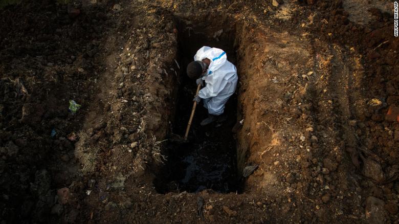 A man in protective suit digs earth to bury the body of a Covid-19 victim in Gauhati, India, on April 25.