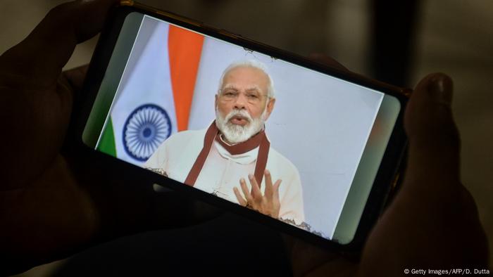 A youth watches Indian Prime Minister Narendra Modi's address to the nation on his mobile phone