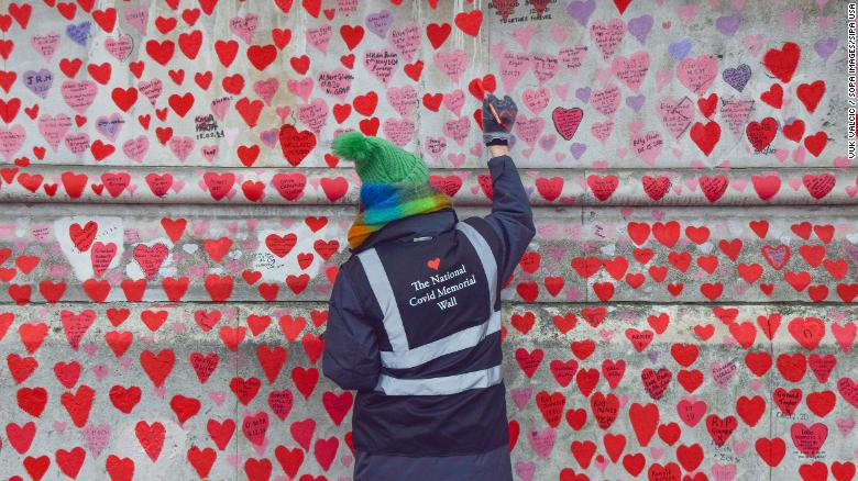 A volunteer paints hearts on the UK's National Covid-19 Memorial Wall.