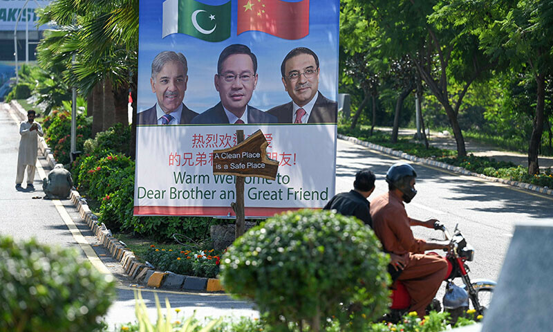 Motorcyclists ride past a billboard featuring images of China’s Premier Li Qiang (C), Prime Minister Shehbaz Sharif and President Asif Ali Zardari (R) at a closed Red Zone near the venue of Shanghai Cooperation Organisation (SCO) summit in Islamabad on October 13. — AFP