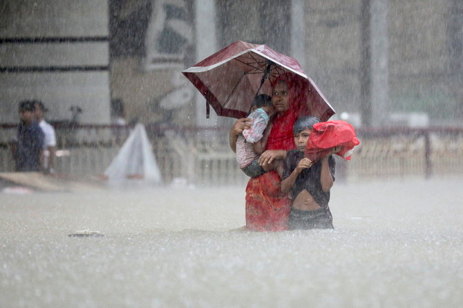 People wade through the water as they look for shelter during a flood, amidst heavy rains that caused widespread flooding in the northeastern part of the country, in Sylhet, Bangladesh, June 18, 2022. (Reuters)