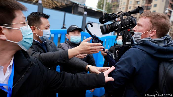 Several men touch and seem to attack a cameraman