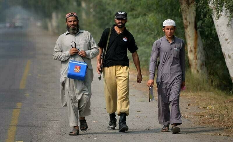 A file photo of polio workers in Khyber Pakhtunkhwa accompanied by a policeman. — Reuters