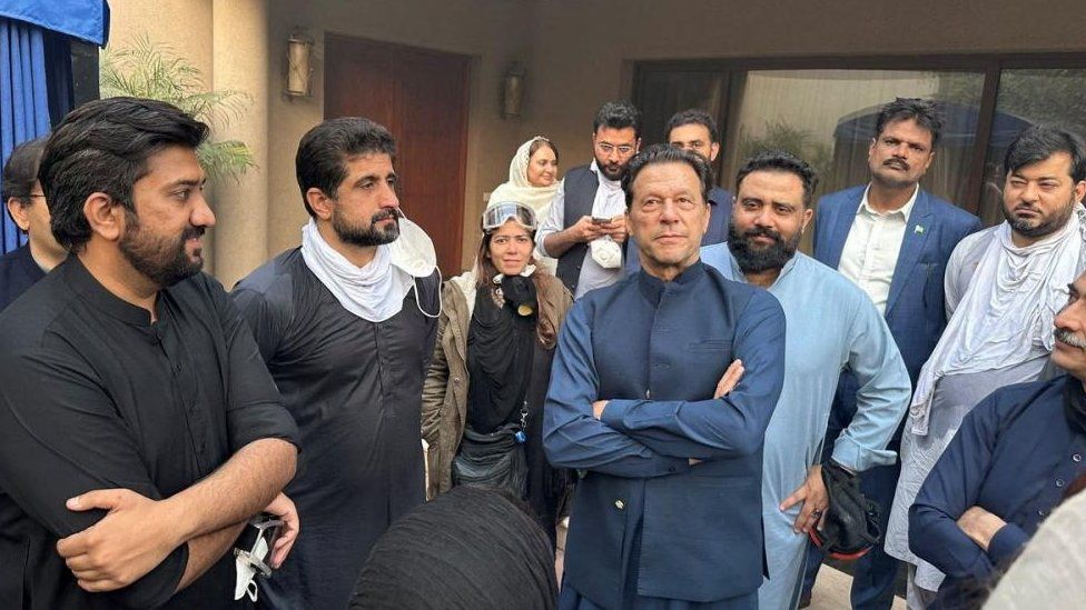 Former Pakistani Prime Minister Imran Khan stands with people in Zaman Park