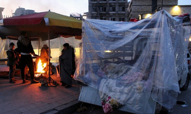 People who evacuated their homes warm up around a fire on a street, in the aftermath of the earthquake, in Aleppo, Syria. — Reuters