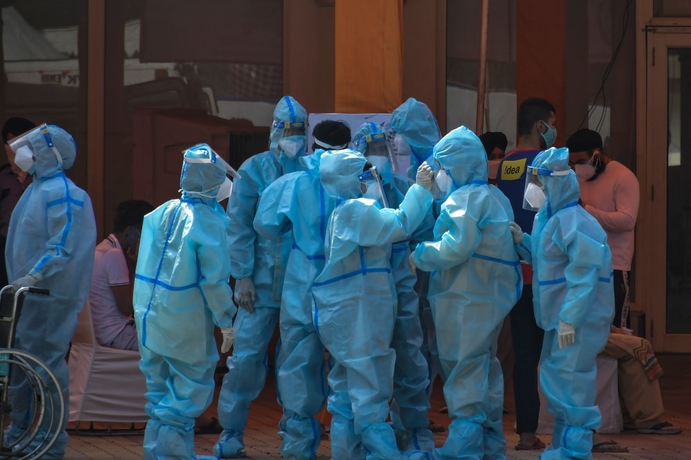 Health workers and volunteers in personal protective suits wait to receive patients outside a Covid-19 hospital in New Delhi. — AP