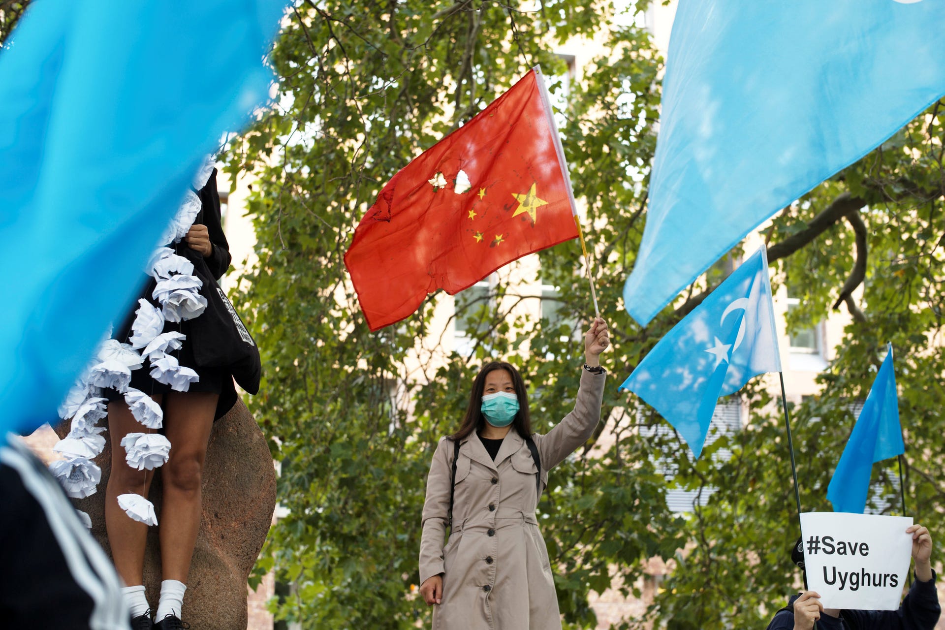 A woman with a partly destroyed Chinese flag amid demonstrators with Uighur flags, in a protest during the visit of Chinese Foreign Minister Wang Yi in Berlin, September 1, 2020.