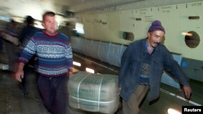 FILE - Uzbek workers carry a pack with blankets delivered from India as they unload a plane in Termez, Dec. 15, 2001. Humanitarian aid for millions of displaced Afghans battling winter cold, disease and hunger were to be distributed through Termez on the border with Afghanistan.