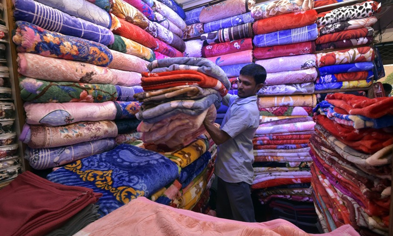 A man arranges Chinese blankets at a market in Dhaka, Bangladesh, on Nov. 23, 2022. Markets in Dhaka are now busy ahead of the peak winter sales season.(Photo: Xinhua)